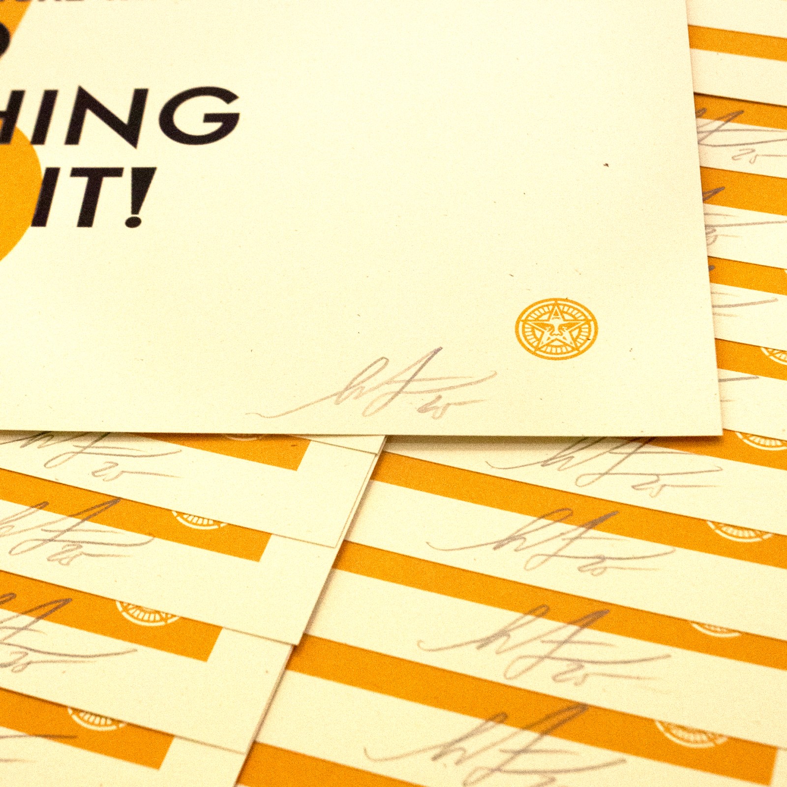 A close-up of the bottom right corner of a poster with a small circular seal and a signature. The poster is surrounded by&hellip;