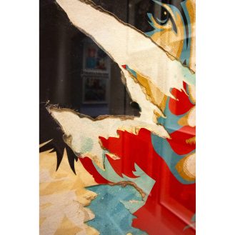 Close-up of a torn poster revealing layers of red, blue, and yellow, with a black background showing through.