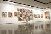 A modern art gallery with white walls displaying numerous framed art prints. Two large prints of bees are on the far left…