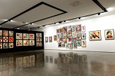 A modern art gallery with white walls on the right displaying numerous framed art prints. A black wall on the left displays…