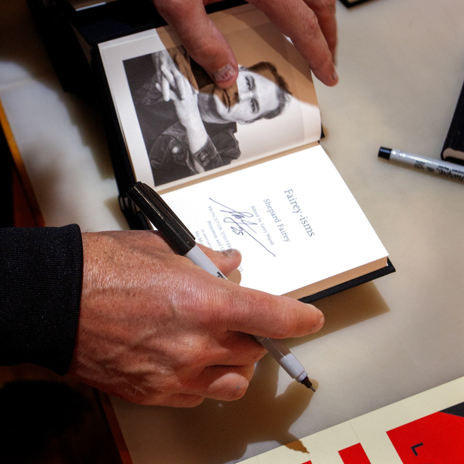 Hands signing the title page of the book