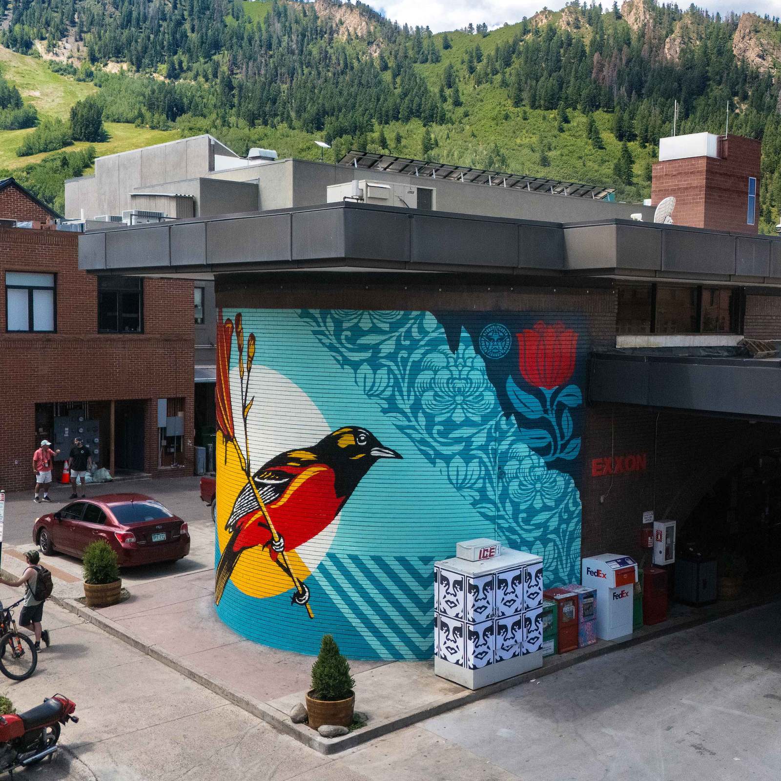 Mural of a bird on a teal background, with flowers and an Exxon sign.