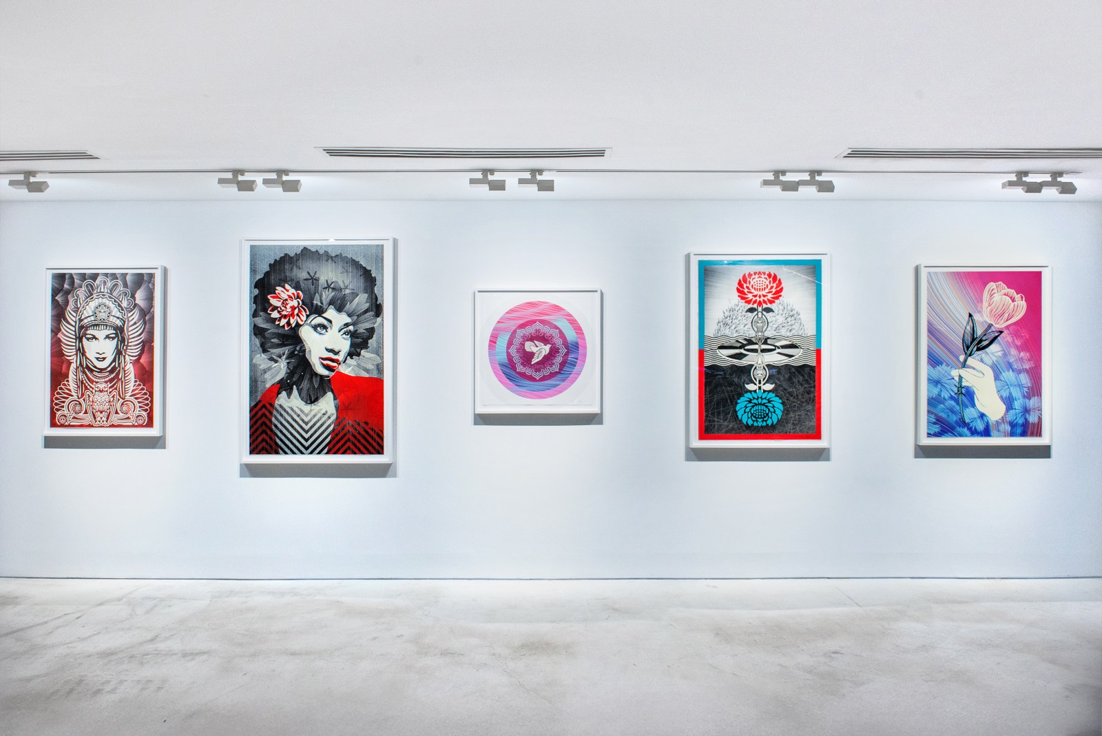 A white art gallery wall featuring five colorful pop art prints, including portraits of women and abstract floral designs.