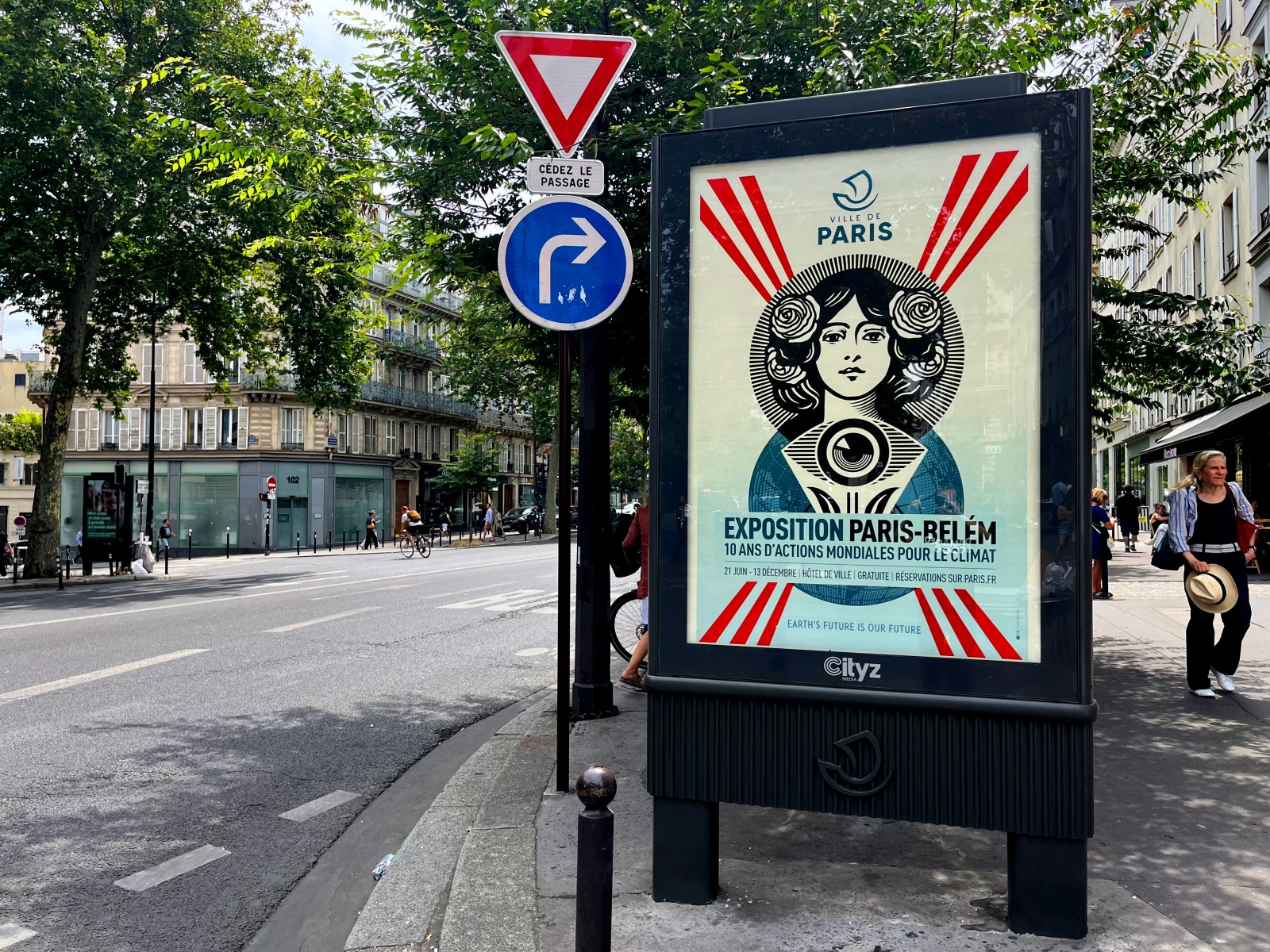 A street scene in Paris with a billboard displaying a poster for 'Exposition Paris-Bel&eacute;m' featuring a stylized woman and&hellip;
