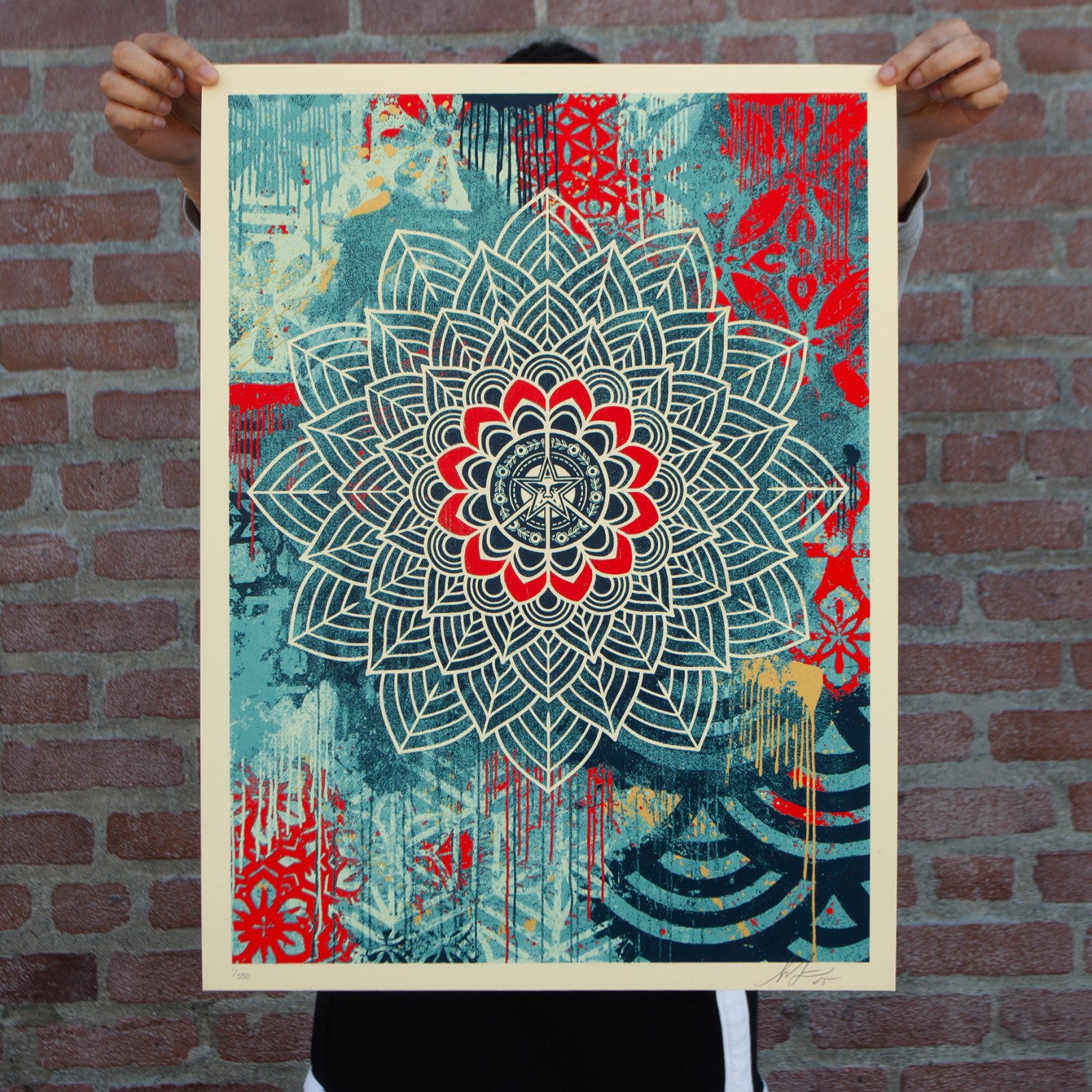 Hands holding a vibrant pop art print featuring a detailed mandala design in blue, red, and cream with distressed textures&hellip;