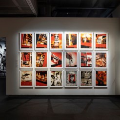 A gallery wall filled with framed art prints, predominantly in red, black, and white, featuring portraits and graphic…