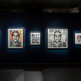 A dark blue gallery wall with four framed art prints. The first is a colorful portrait, the second a black and white face…